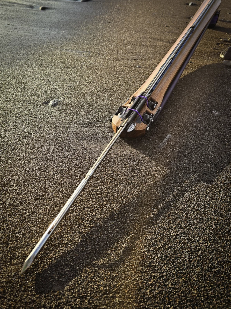 Handcrafted speargun tip on dark sand